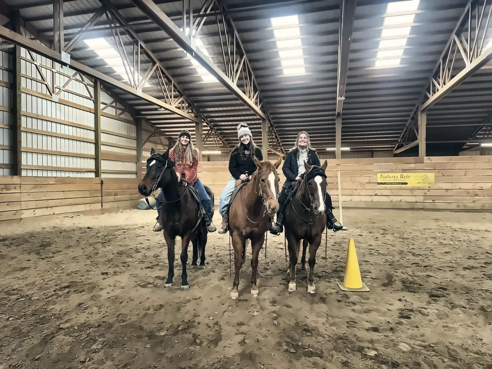 Three riders lined up in the indoor arena